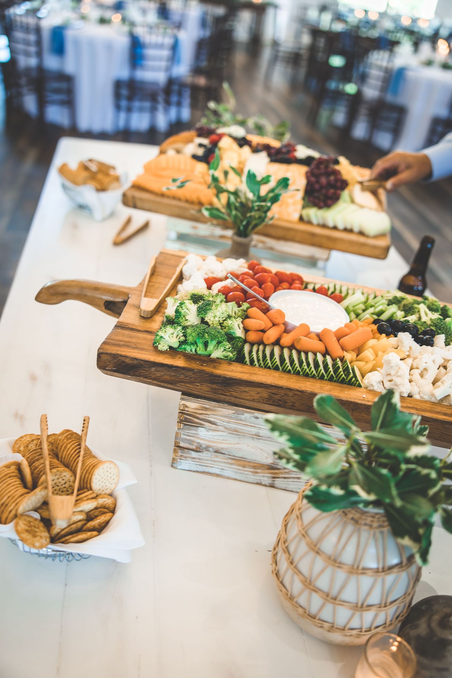 Elegant appetizer spread on wooden serving boards with cheese, crackers, and fresh vegetables.