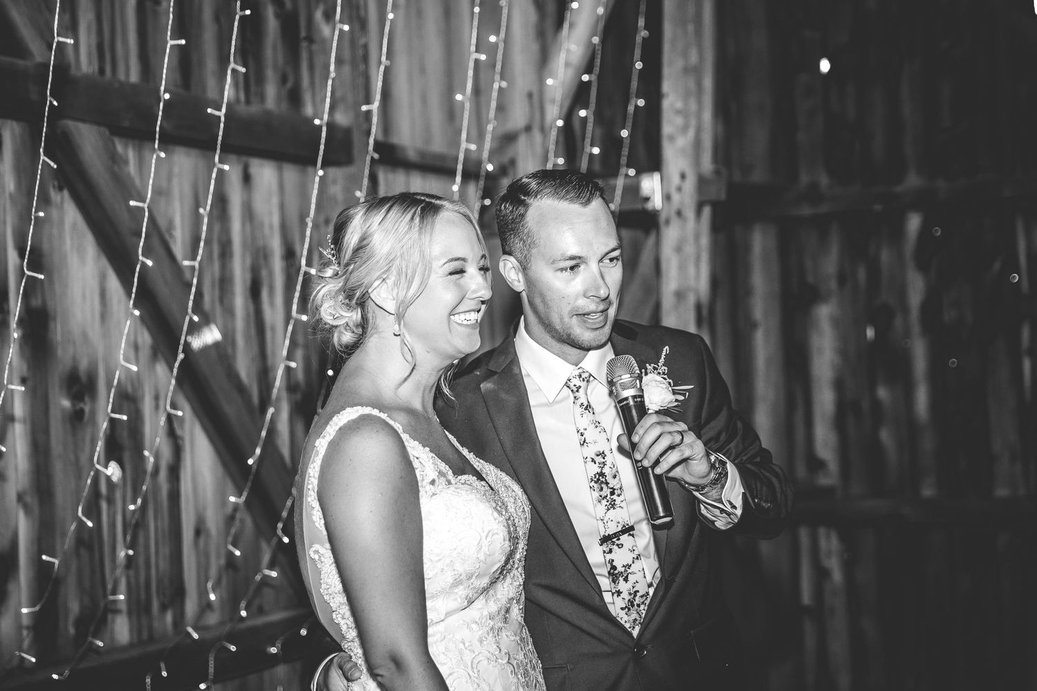 Wedding celebration in full swing with dancing couples under twinkling barn lights.