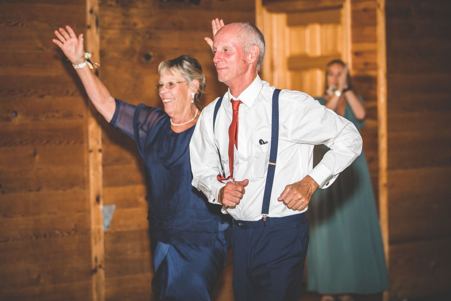 Wedding reception dancing in rustic wooden barn venue with warm lighting.