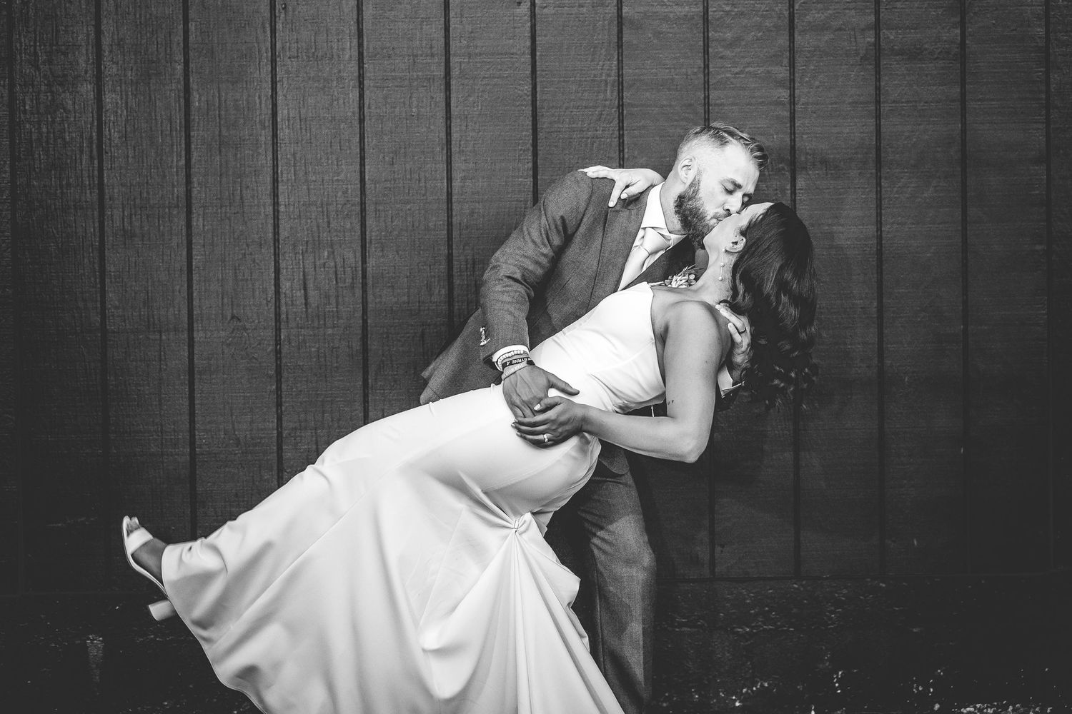 A dramatic black and white wedding photo showing a romantic dip pose.