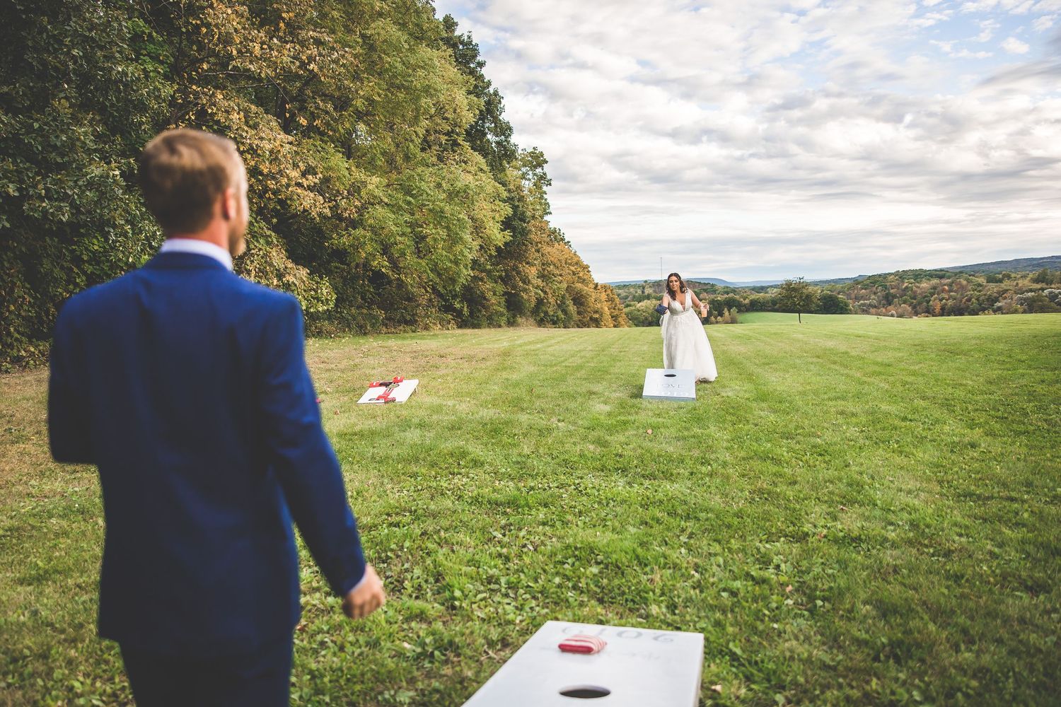 Wedding couple shares intimate moments in a scenic outdoor field with rolling hills and autumn foliage.