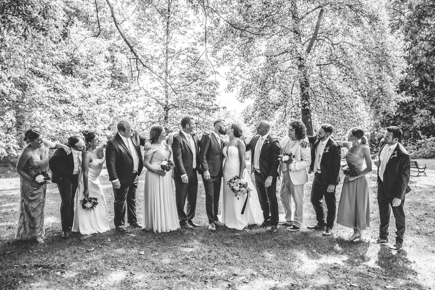 Black and white wedding party portrait captured in natural outdoor setting.
