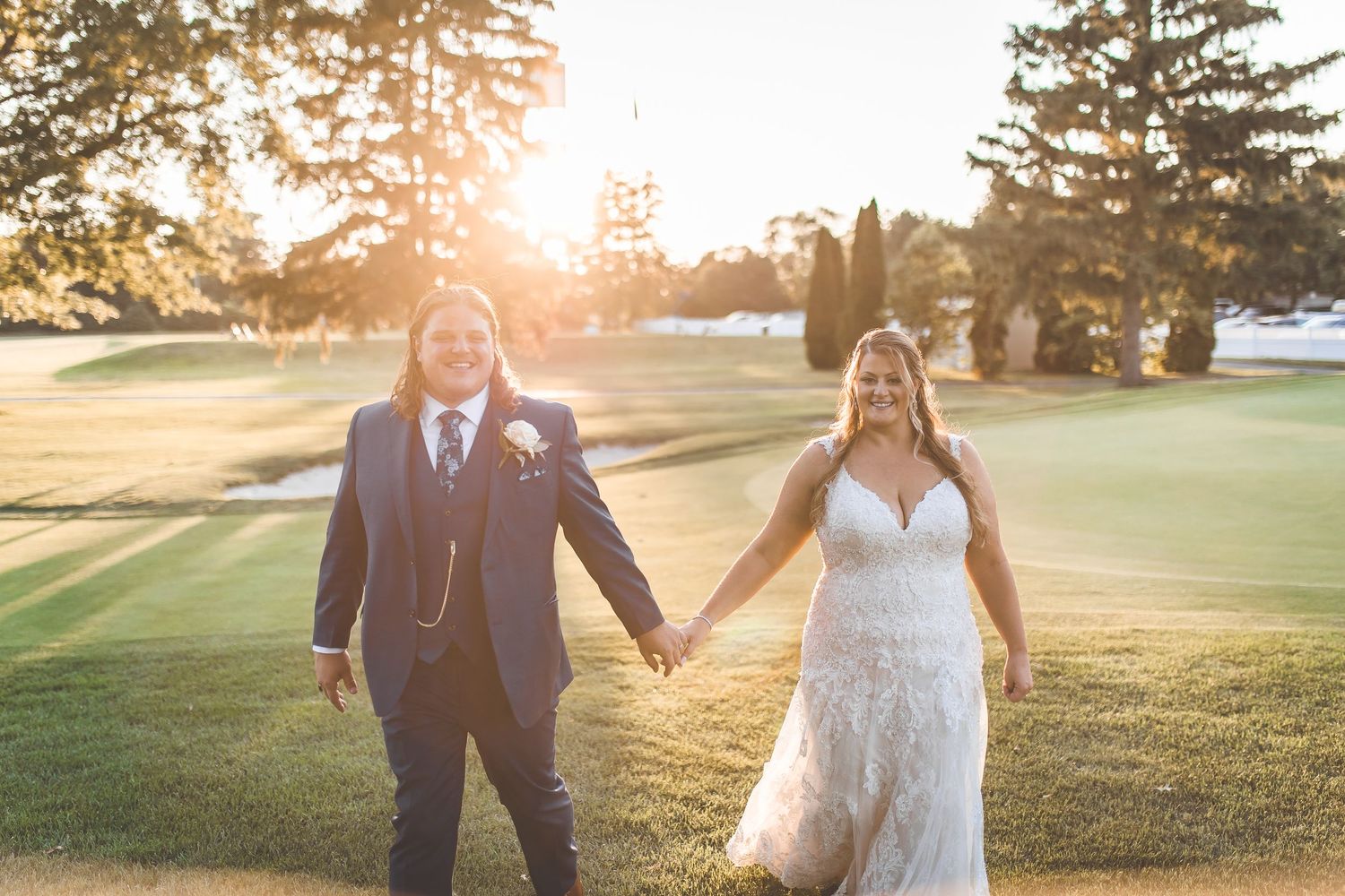 Wedding couple sharing romantic moments at sunset on a golf course.