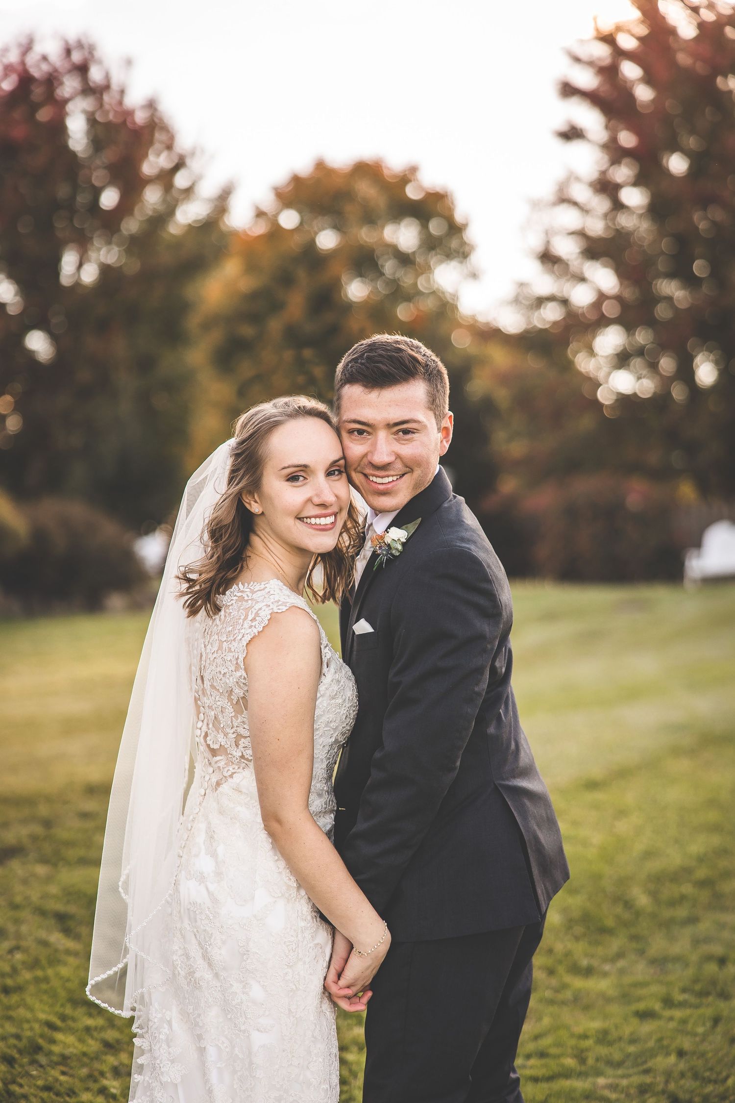 Autumn wedding portrait of couple in formal attire on grassy hillside.