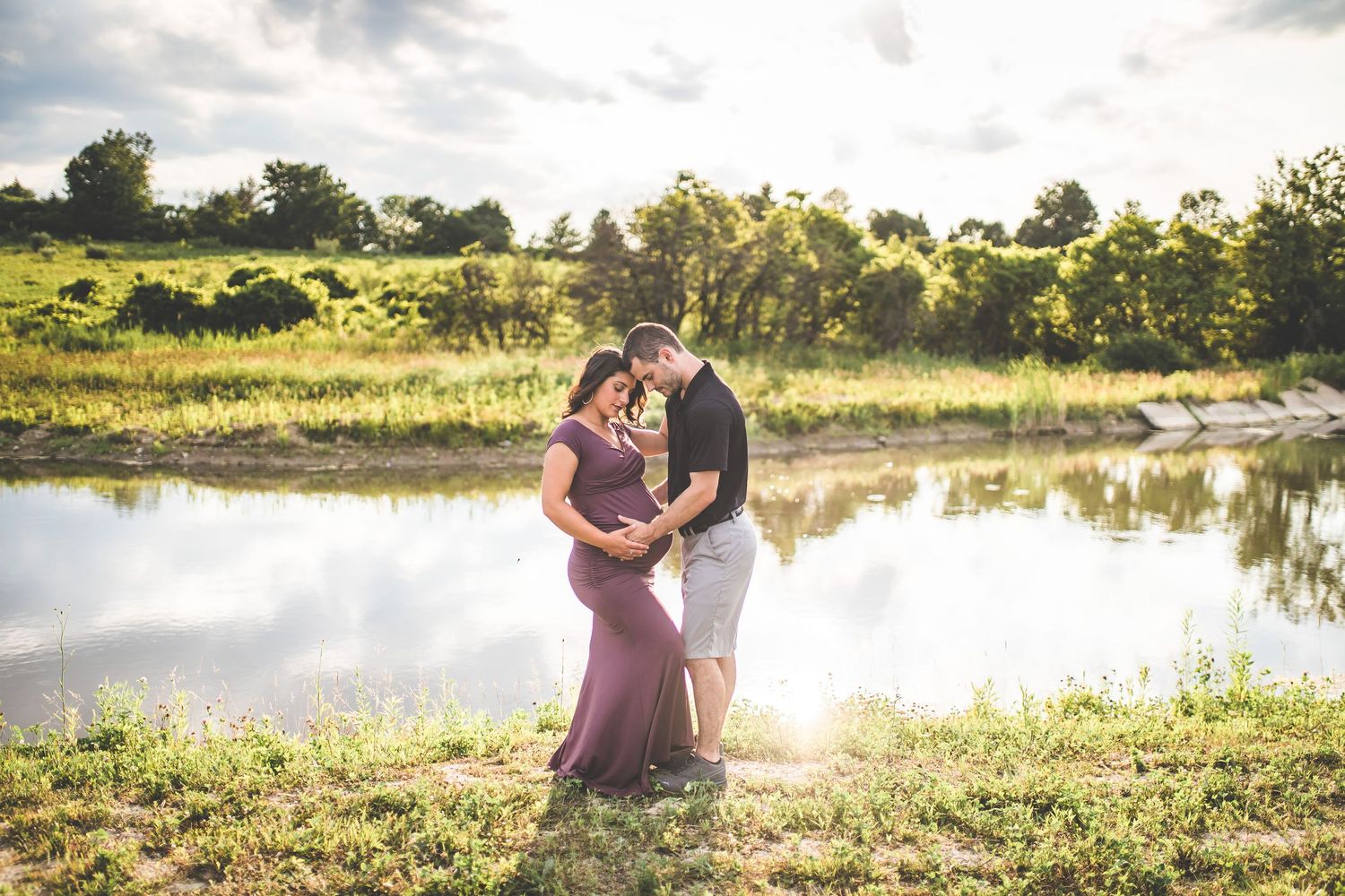 Romantic sunset engagement photos captured by a lake with golden hour lighting.