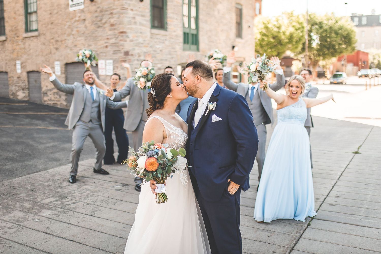 Wedding guests gathered outside a historic brick building for outdoor celebrations.