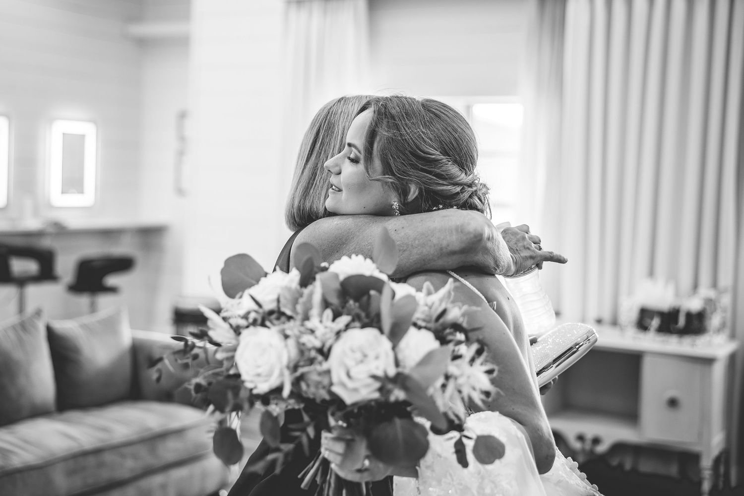 Wedding party members pose in black and white during preparation moments in a bright indoor setting.