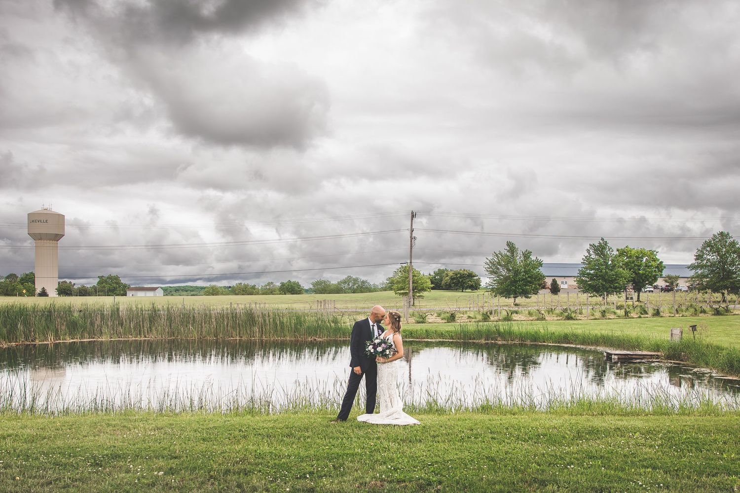 A romantic lakeside wedding portrait with a water tower in the background.