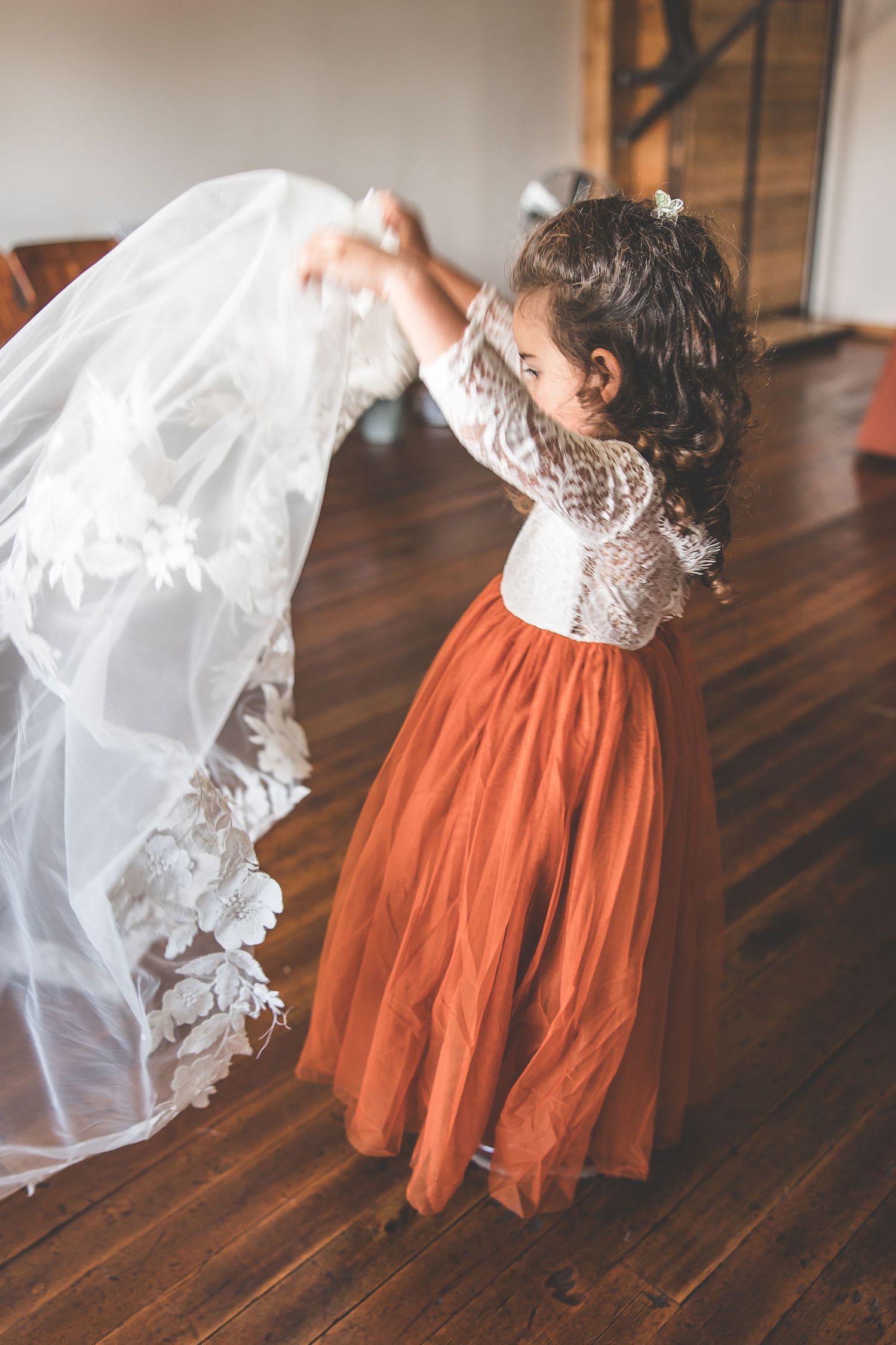 Wedding dress detail shot showing contrast between white lace bodice and rust-colored skirt.