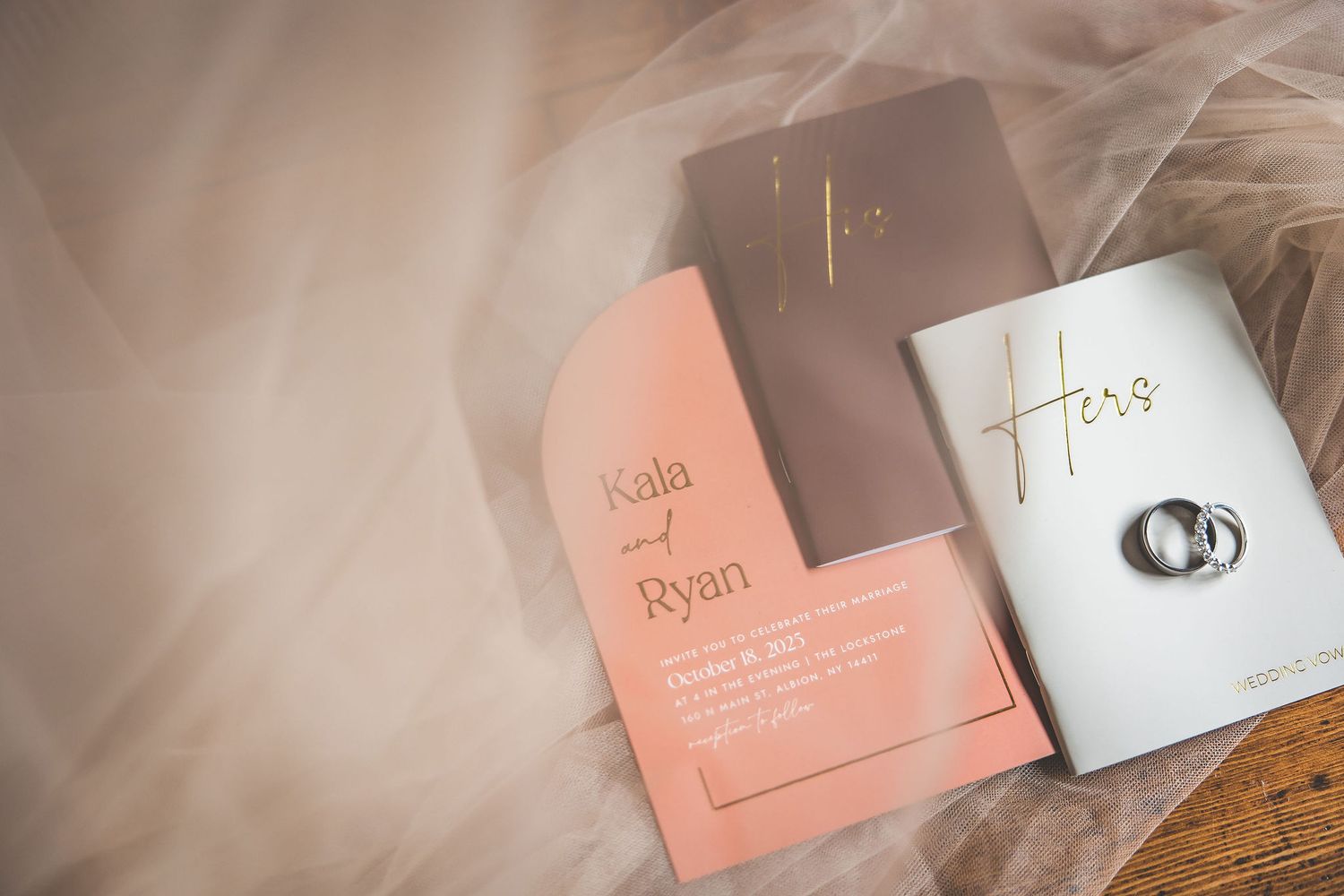Wedding invitation suite in peach and white colors with modern typography laid out on a table.