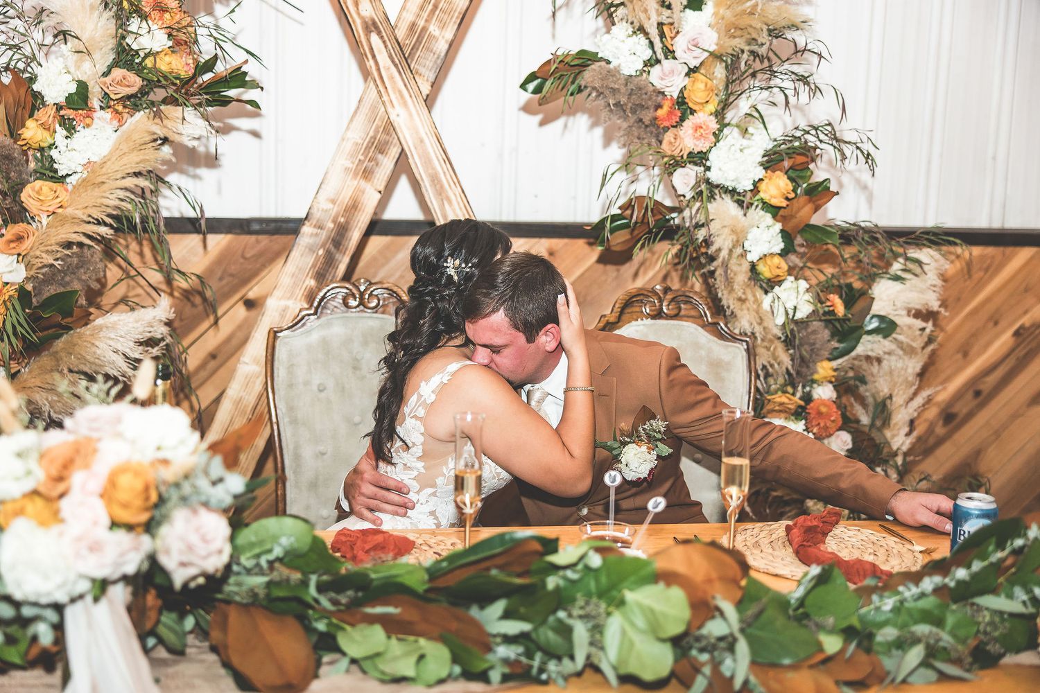 Elegant wedding reception space decorated with wooden elements and autumn-colored florals.