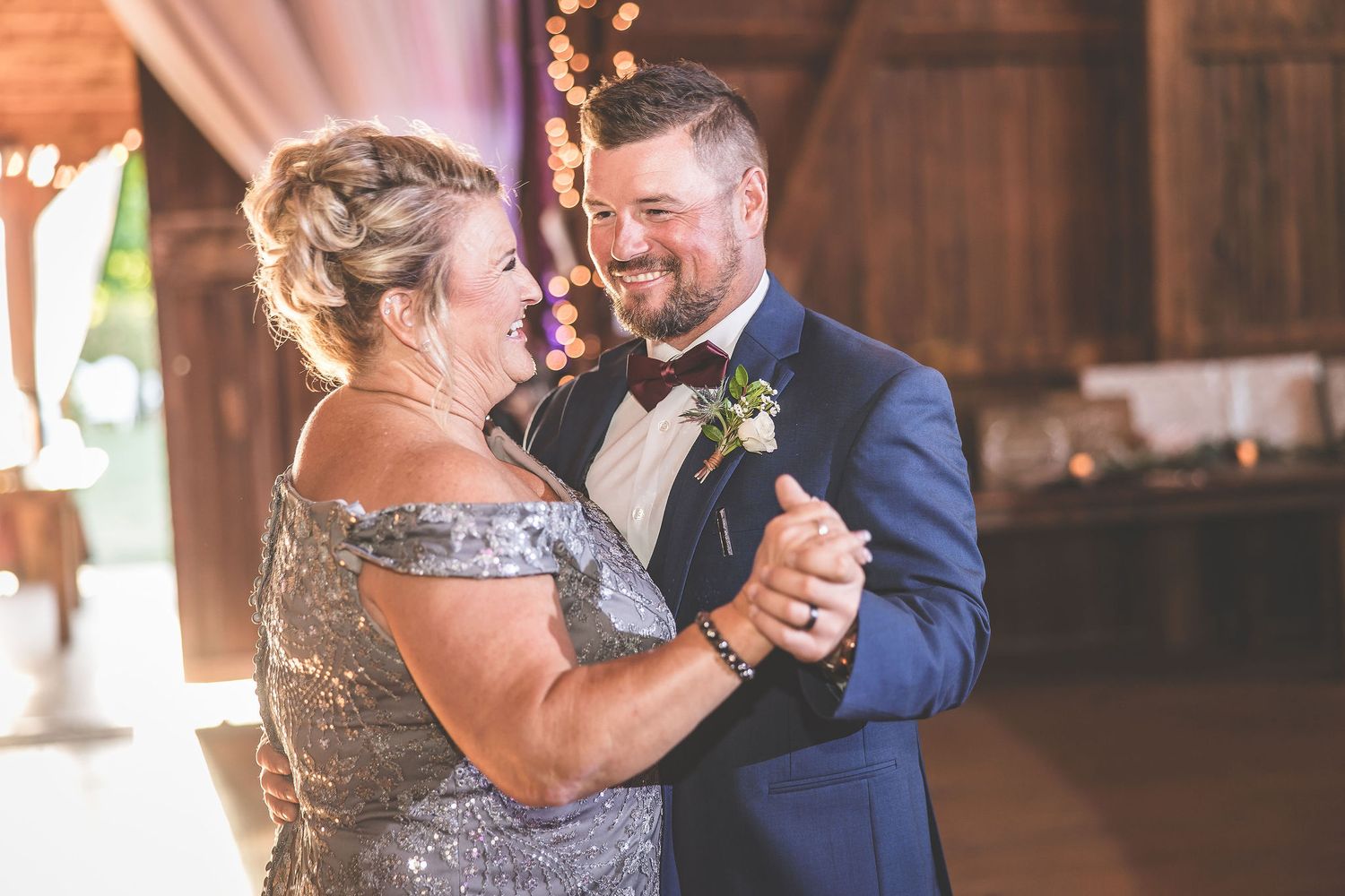 Emotional dance moment between wedding guests in a beautifully lit barn venue.