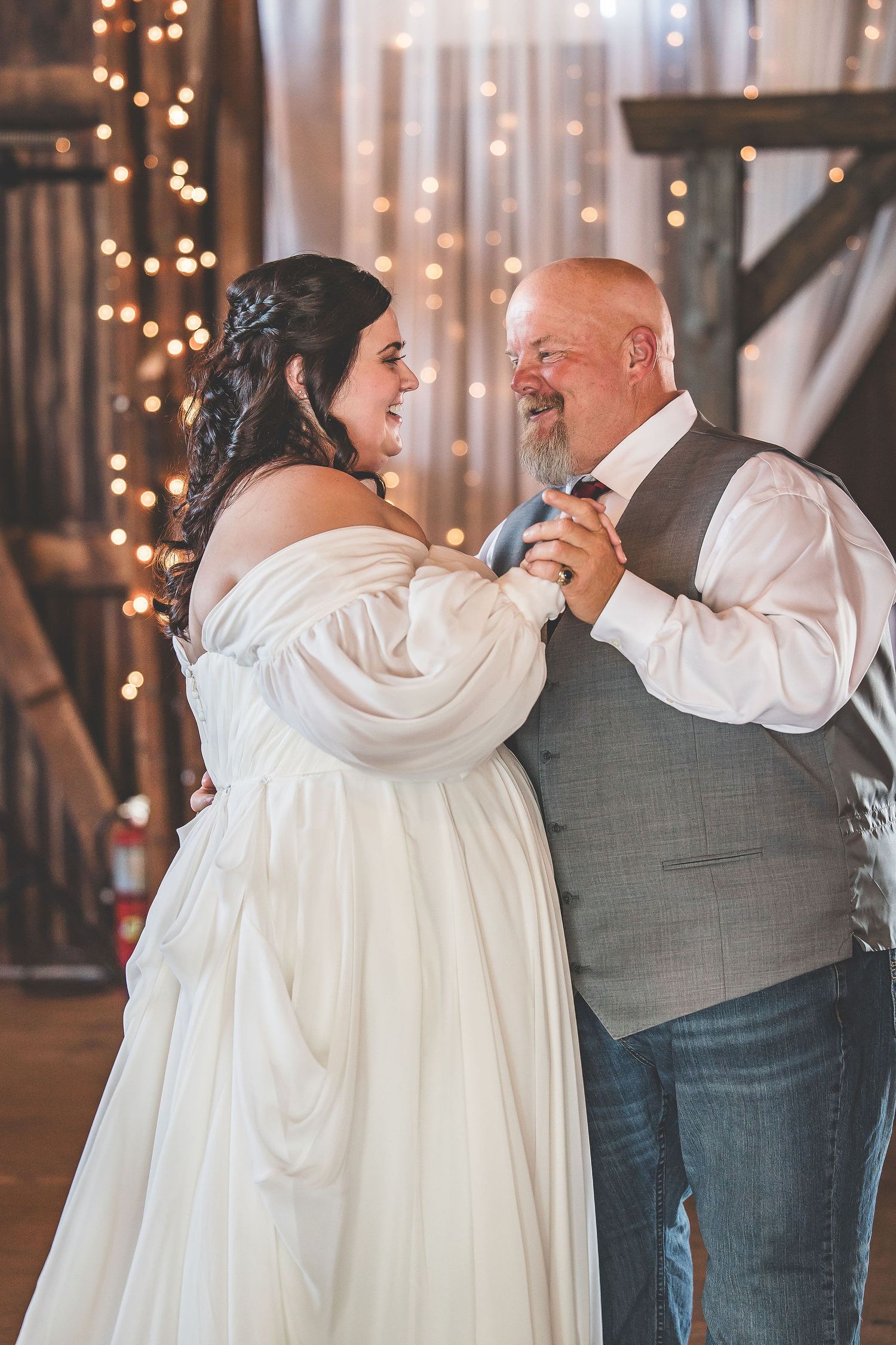 Wedding dance in a rustic barn venue illuminated by romantic string lights.