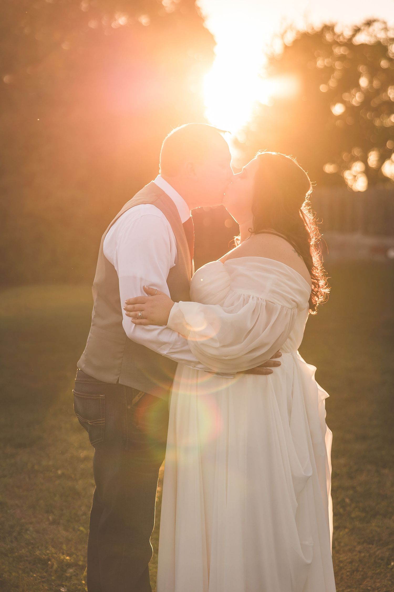 Silhouetted couple embraces in golden sunset light during their wedding photoshoot.