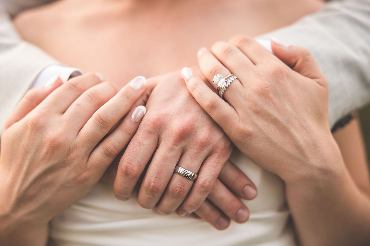 Close-up of wedding rings and intertwined hands showing intimate connection.