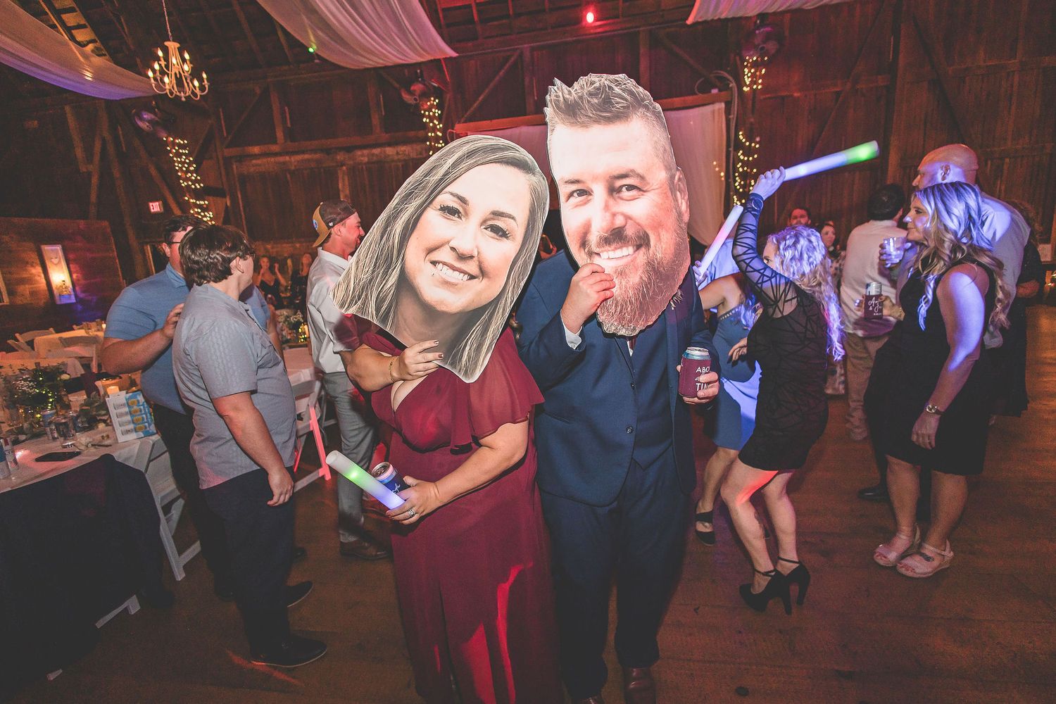 Lively dance floor scene at a barn wedding with colored lighting and fabric decor.