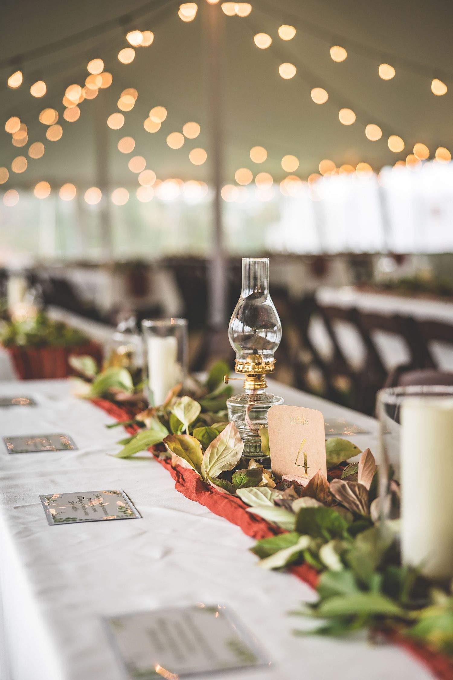 Elegant wedding reception tables set under twinkling string lights with white linens and floral centerpieces.