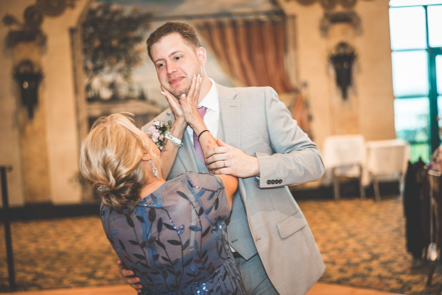 Wedding celebration in a luxurious venue with decorative wall details and large windows.