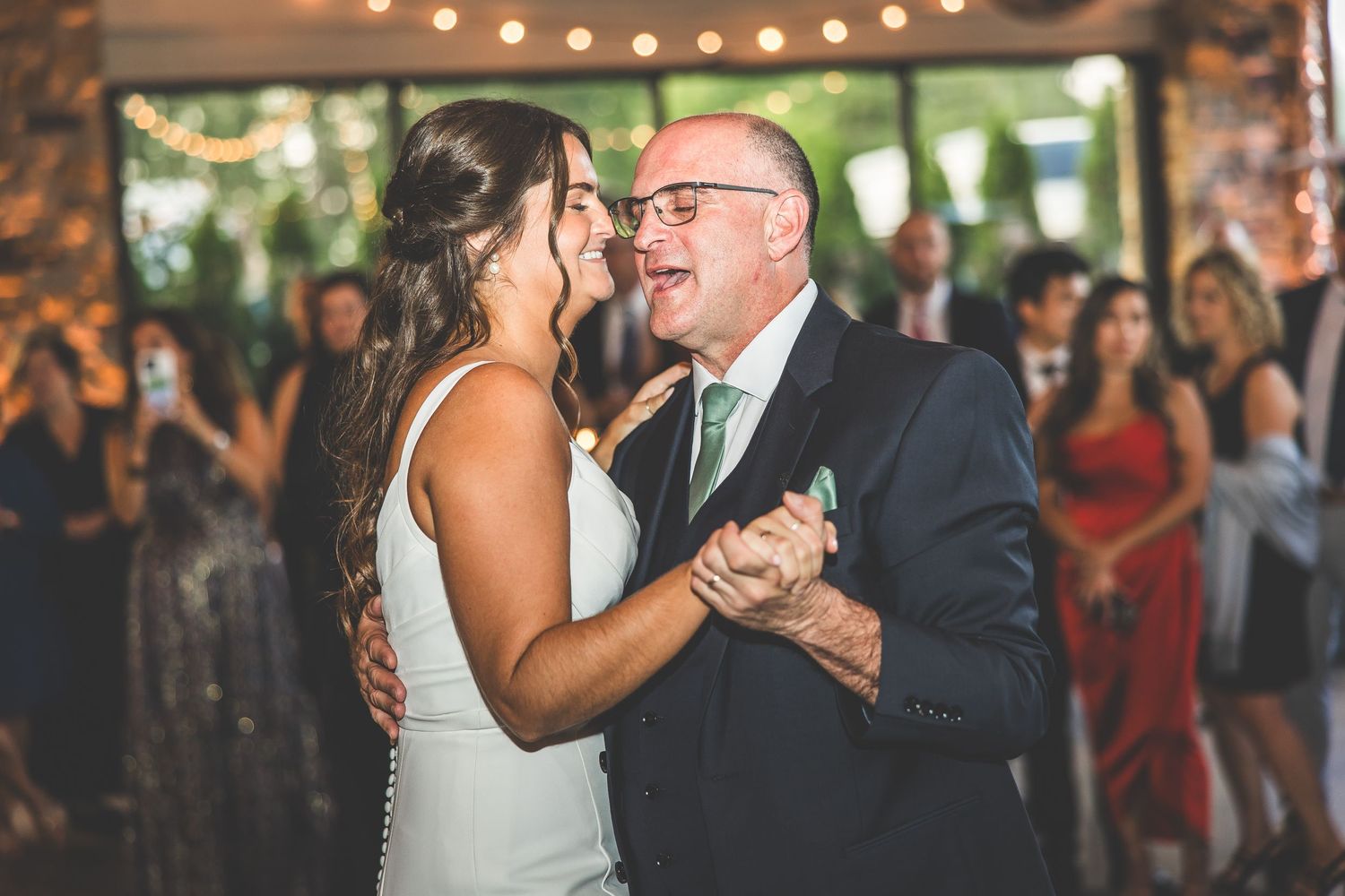 Couple shares their first dance surrounded by guests at an elegant indoor reception.