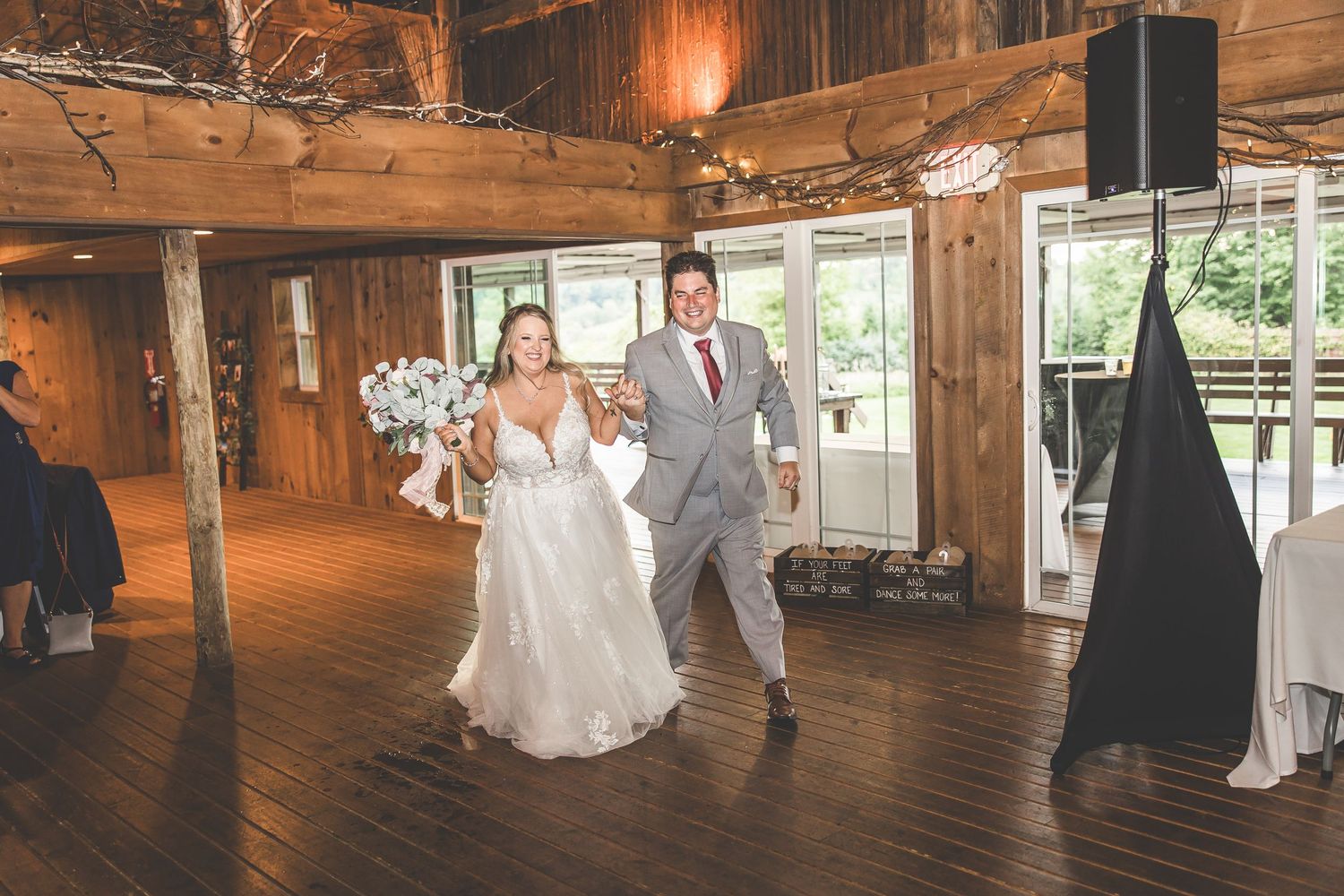Couple shares their first dance in a rustic barn venue decorated with warm lighting and wooden beams.