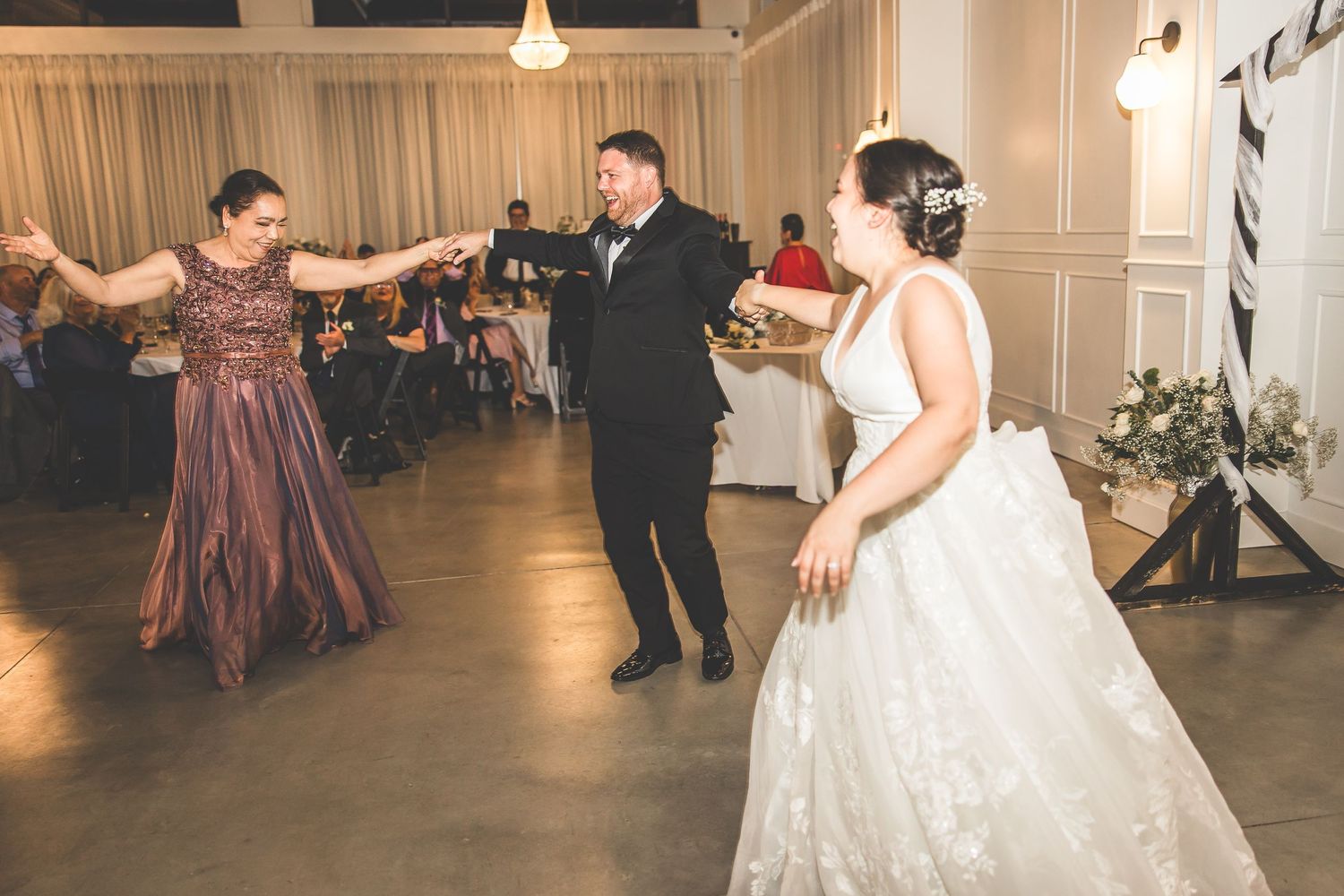 Wedding celebration with dancers twirling on a polished dance floor surrounded by seated guests.