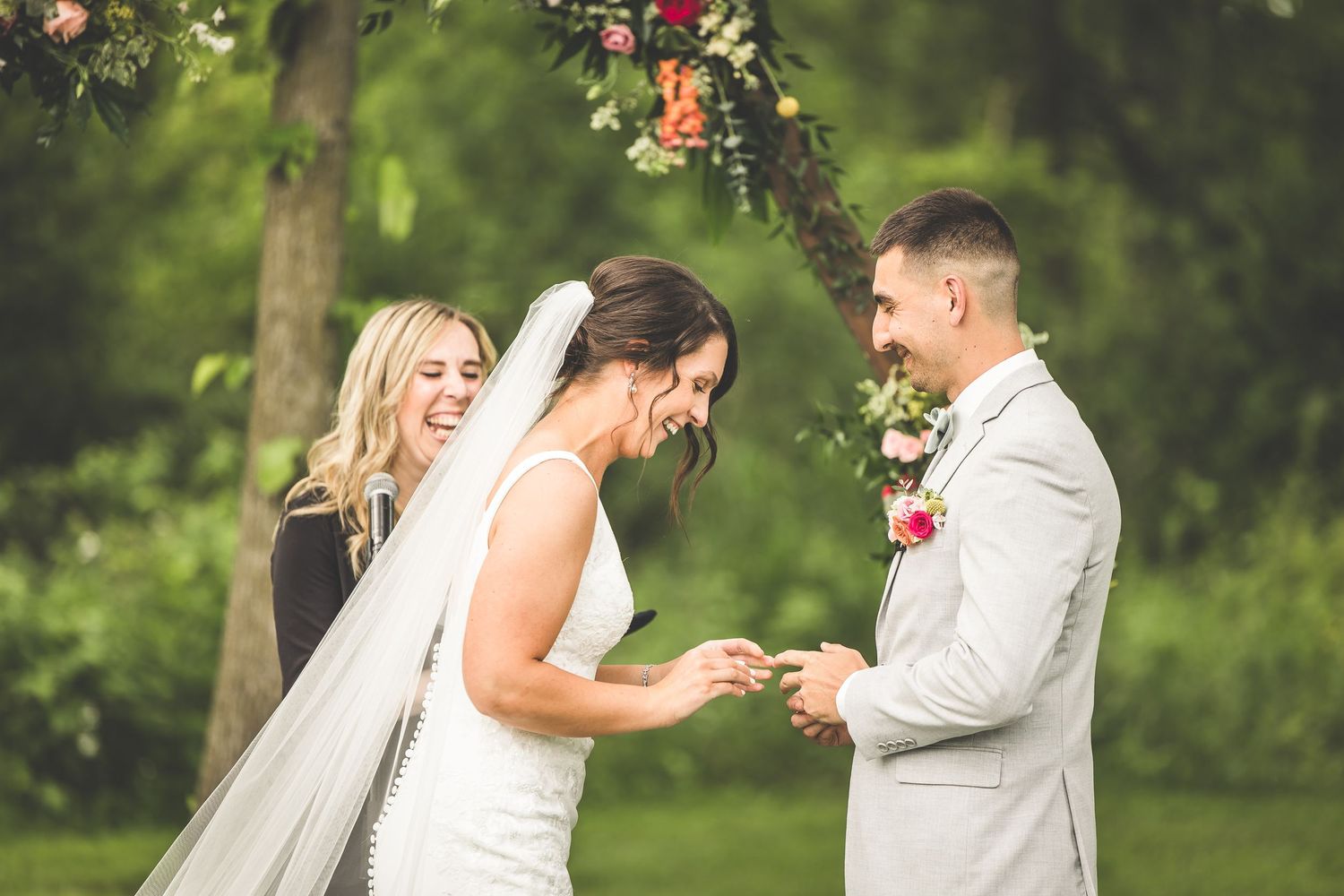Emotional ring exchange moment during outdoor garden wedding ceremony.