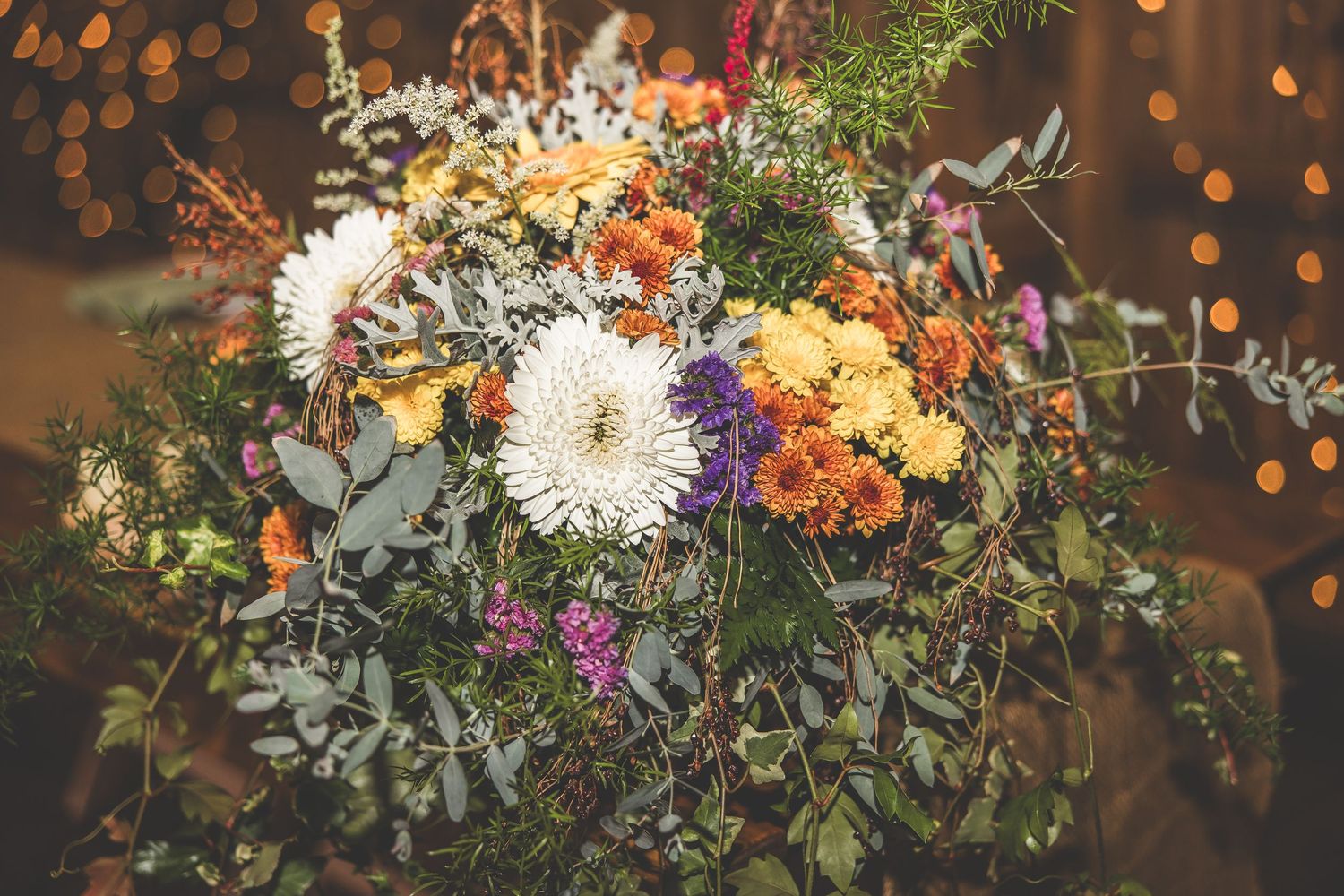 Elegant floral centerpiece with orange and white flowers against bokeh light background.