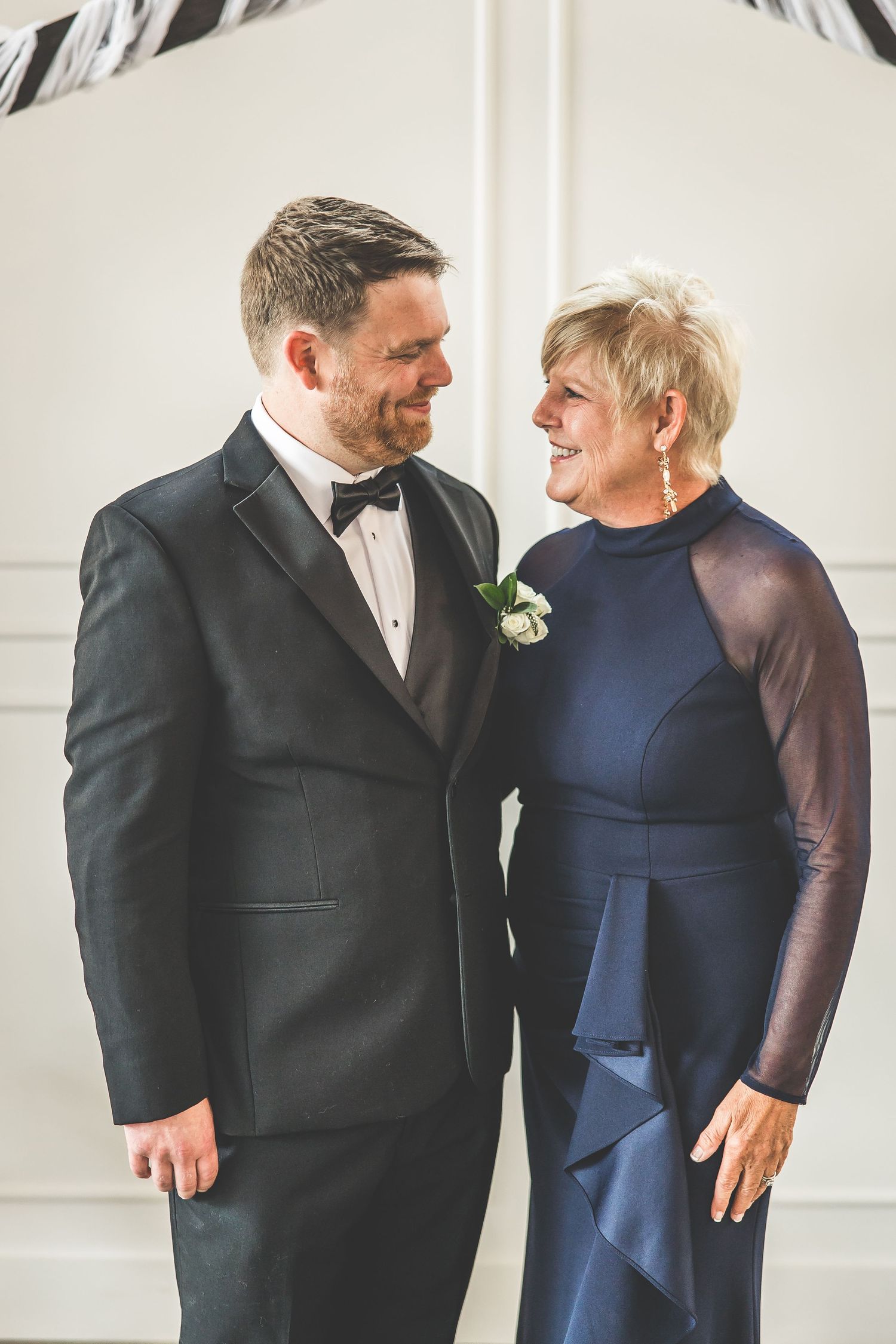 Wedding party members share laughs and embraces in formal attire.