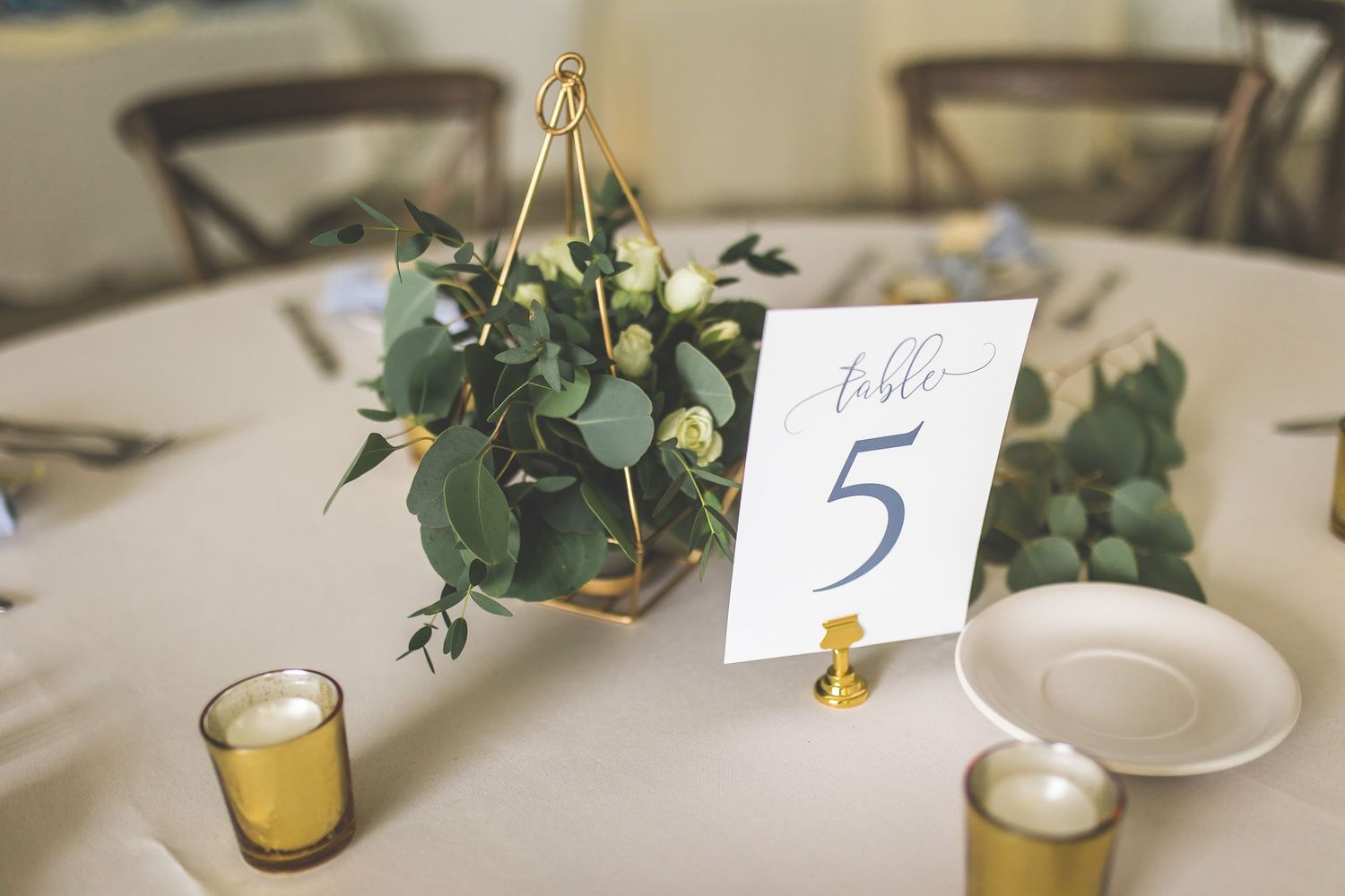 Wedding reception table settings with greenery decor and numbered place cards.