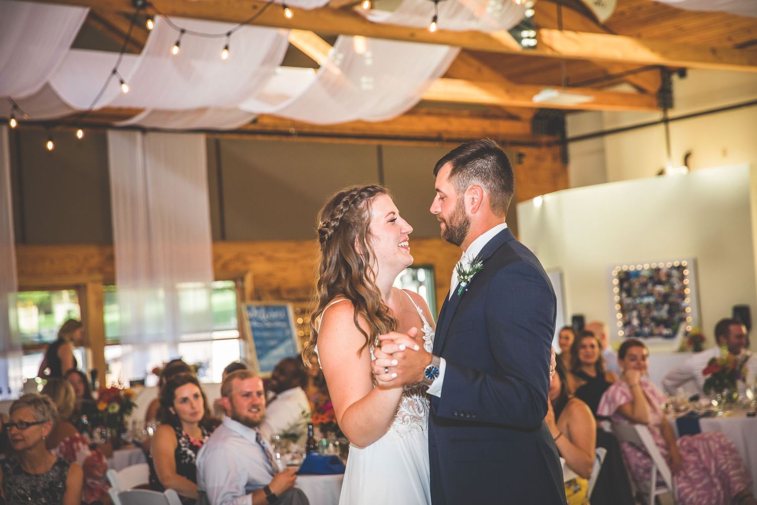 Couples dancing at wedding reception under white fabric draped ceiling and warm lighting.