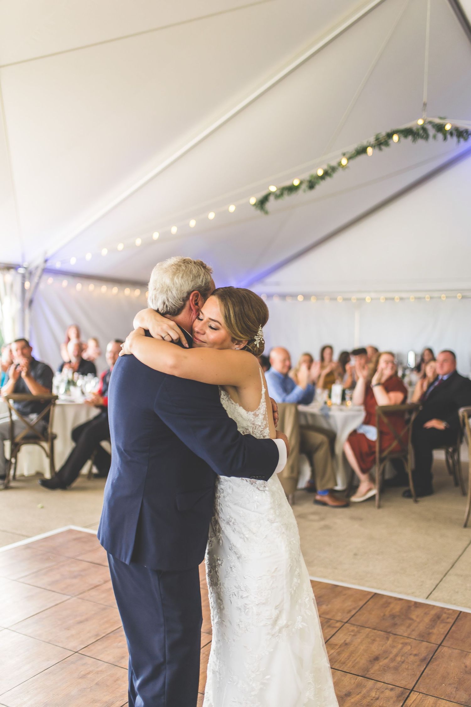 A heartfelt dance between two people during a wedding celebration in a decorated tent venue.