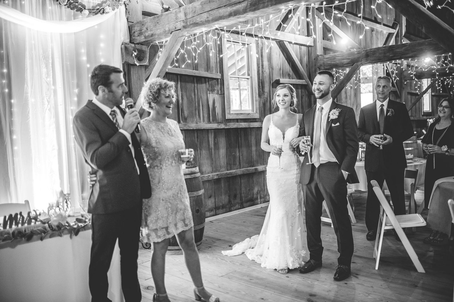 Indoor barn wedding ceremony with rustic wooden beams and white decor.