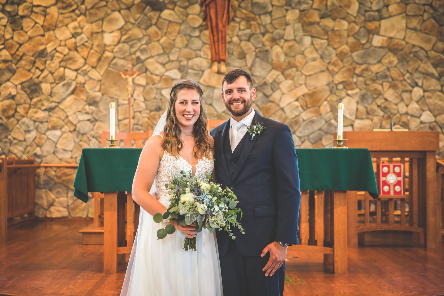 Intimate wedding ceremony taking place in a beautiful stone chapel with natural lighting.