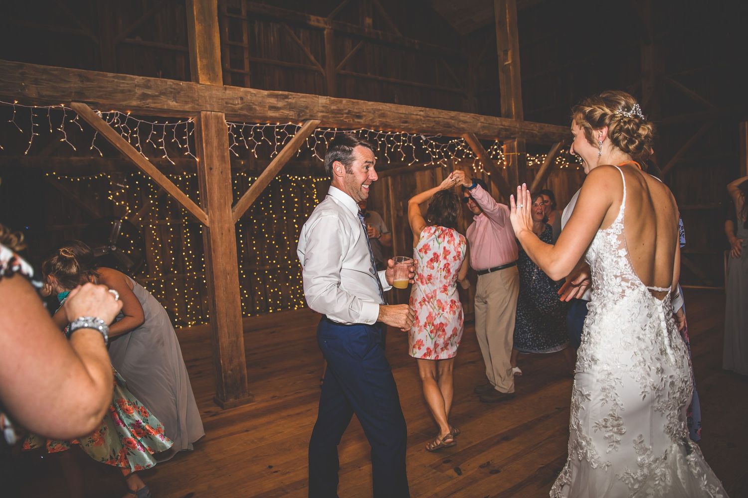 Wedding reception dance floor with string lights creating warm ambiance in rustic barn.