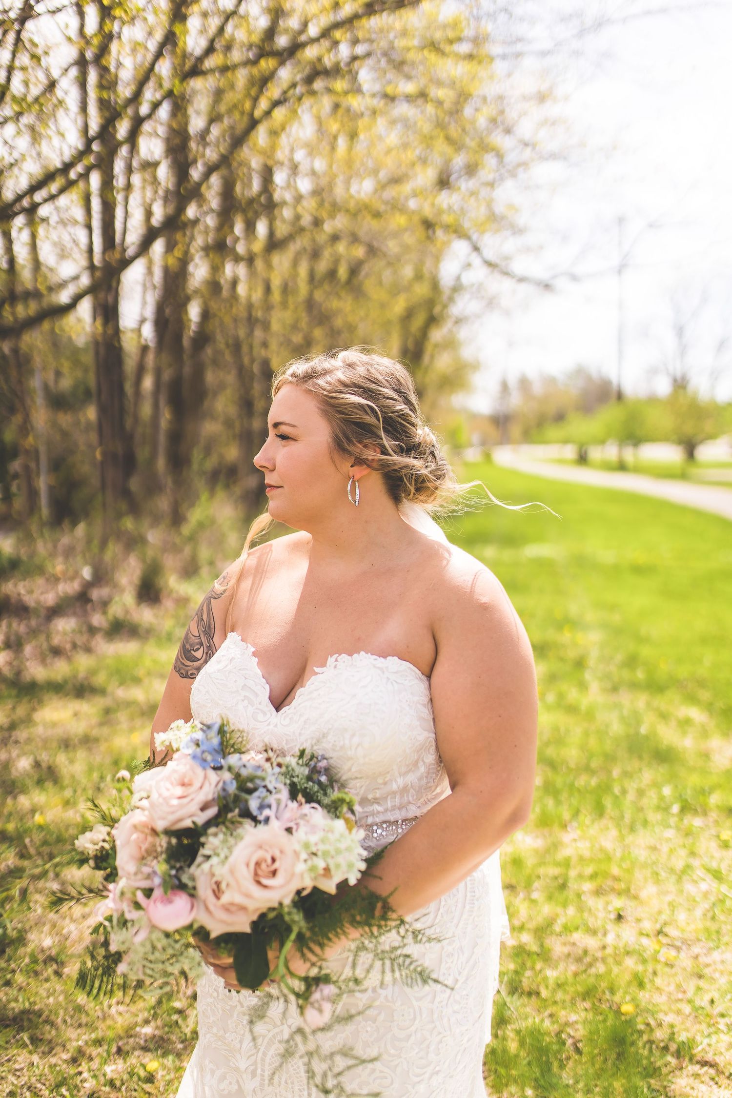 A bridal portrait showcasing a bouquet of pink and white flowers against a natural spring background.