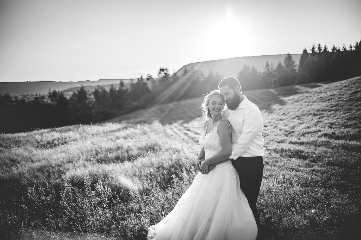 Wedding party holding sparklers in a field at golden hour creating magical light trails.