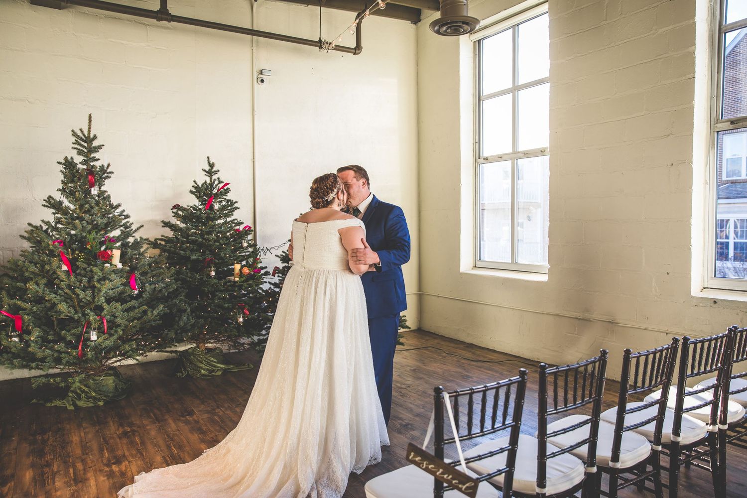 Romantic moment between newlyweds in venue decorated with Christmas trees.