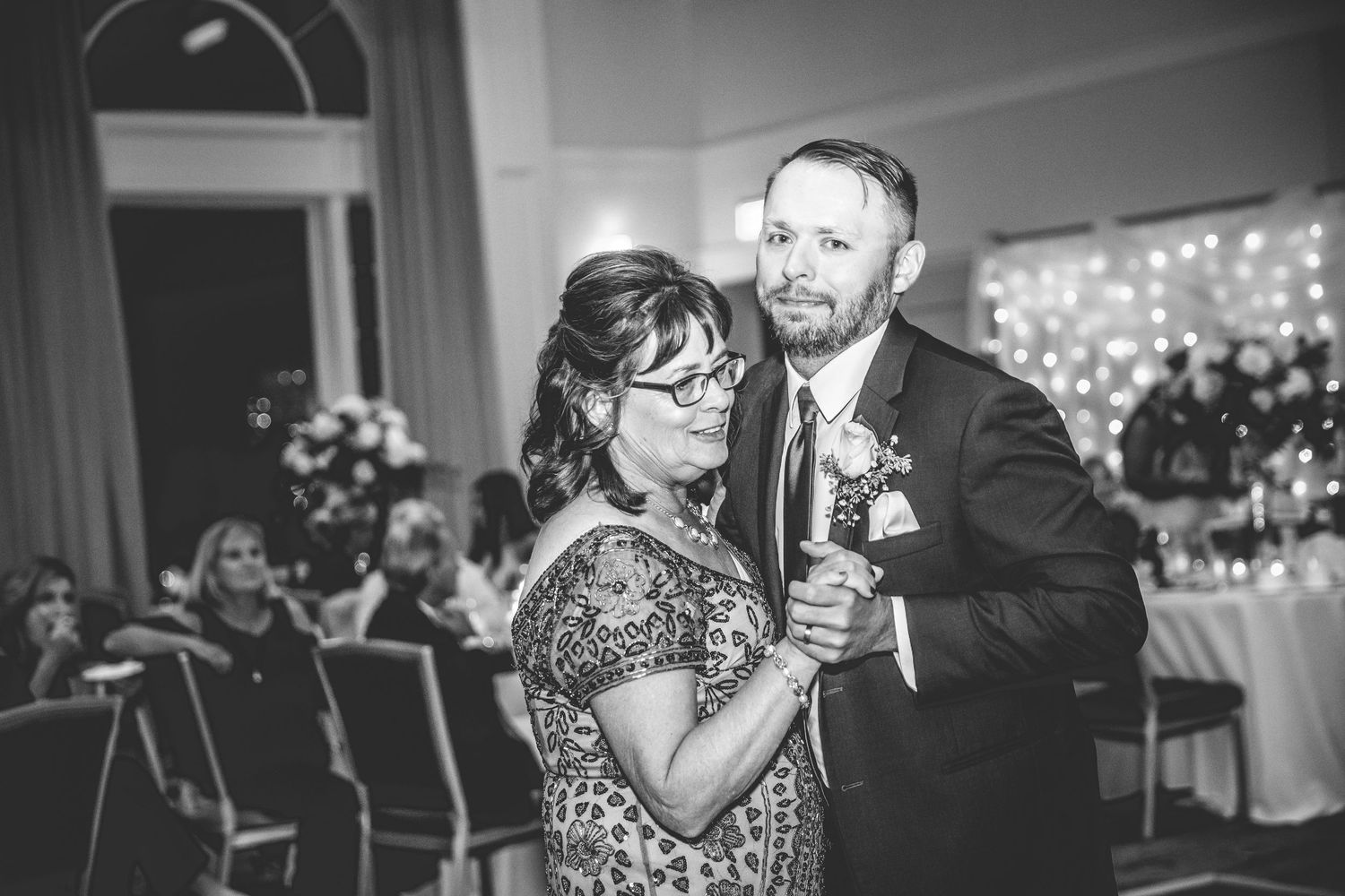 Black and white photo of wedding reception dance in dimly lit ballroom.