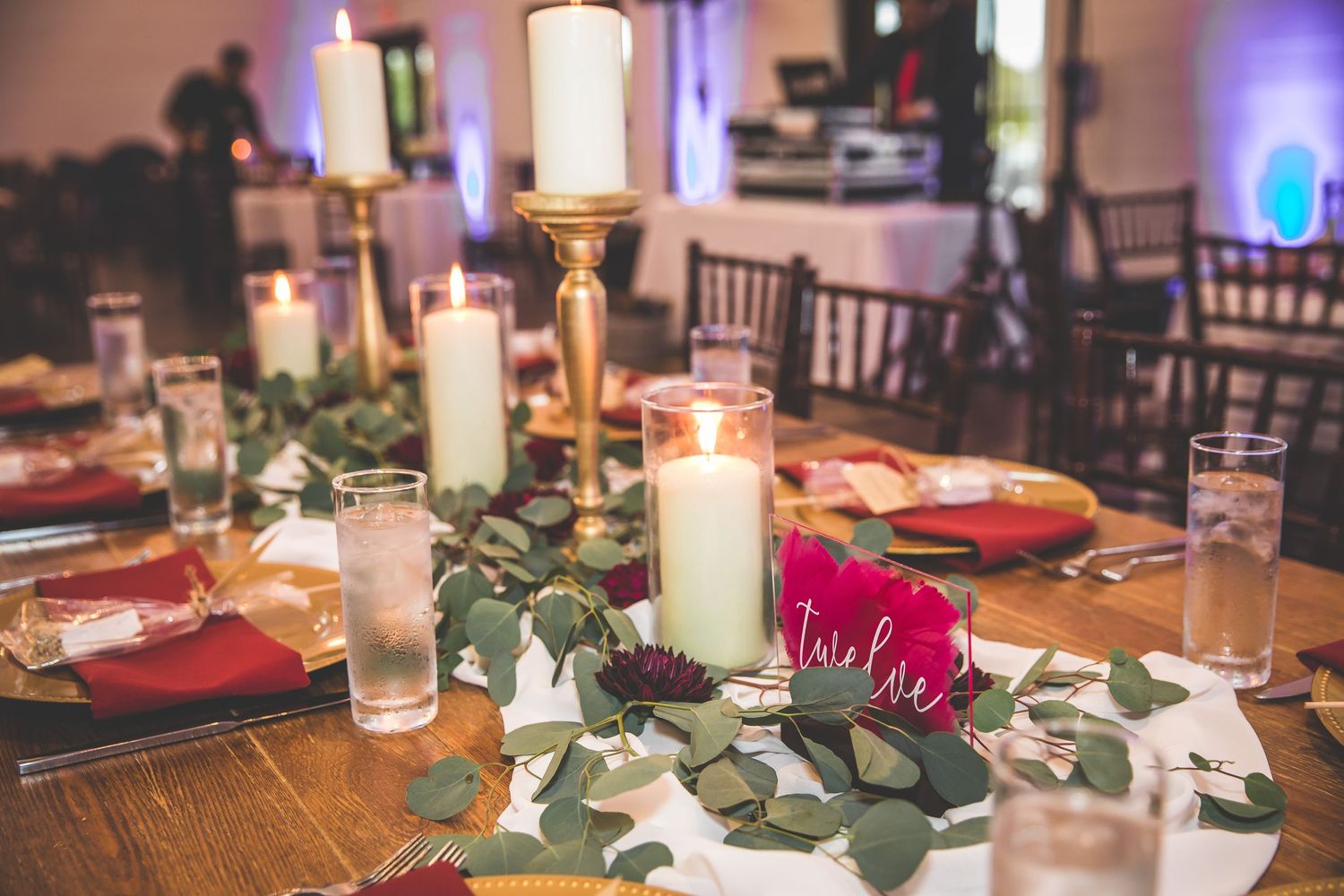 Wedding reception tables decorated with candles and greenery garlands.