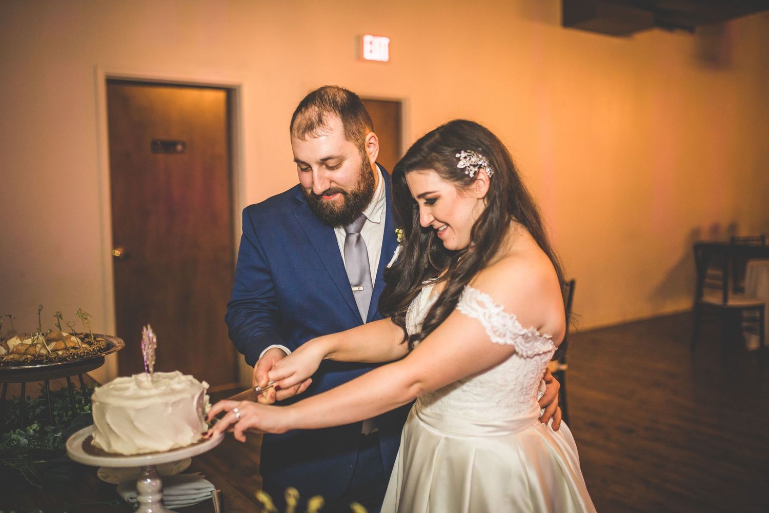 Couple sharing cake-cutting moments during their wedding reception celebration.