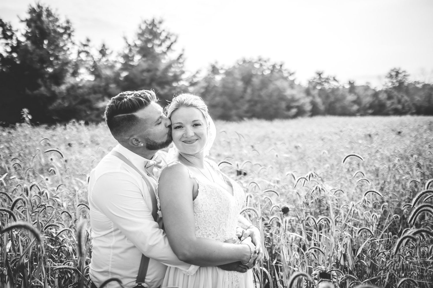 Black and white wedding photos showing intimate moments in a natural field setting.