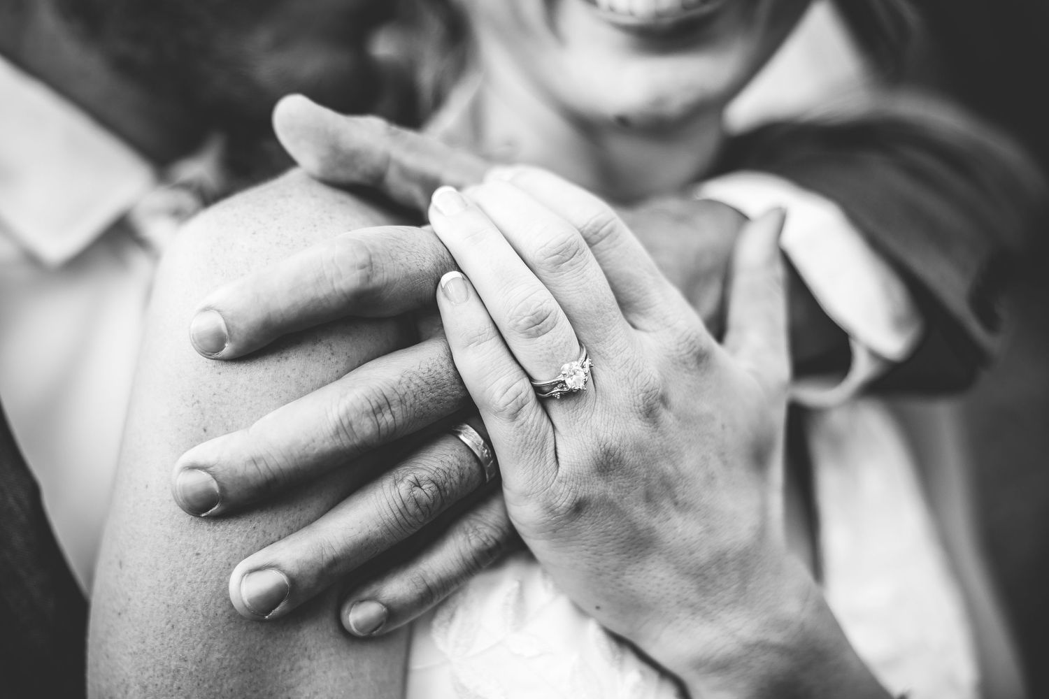 Close up black and white photo of hands with wedding ring during intimate moment.