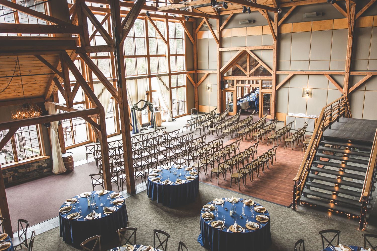 Elegant wedding reception setup with round tables and blue linens in a rustic wooden venue.