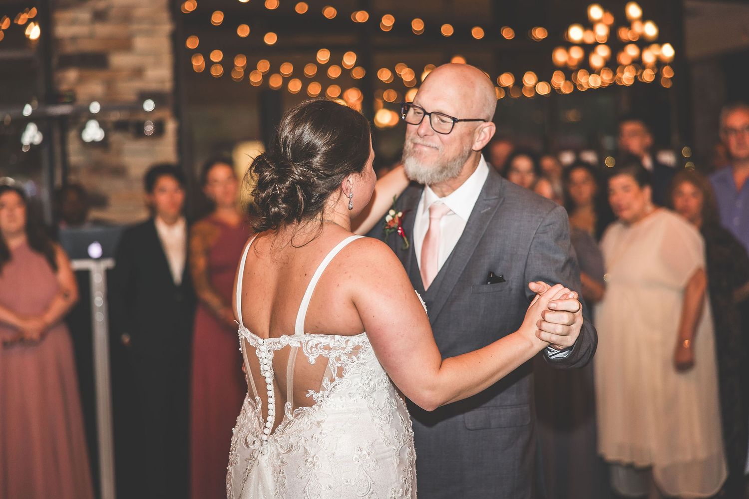 String lights illuminate an elegant indoor wedding reception space.