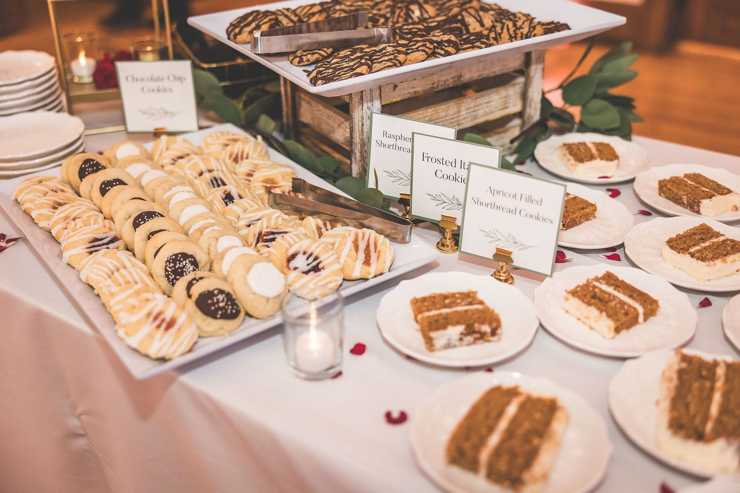 Elegant dessert table with assorted cakes, pastries and sweets displayed at a wedding reception.