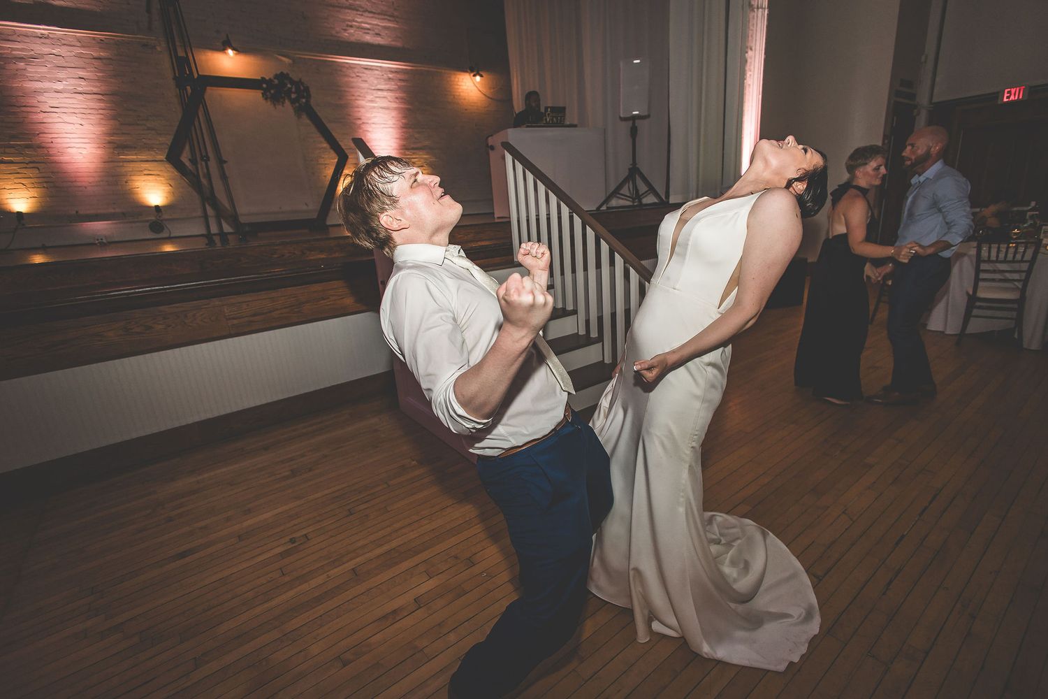Couples dancing together during a wedding reception in an elegant ballroom with warm lighting.