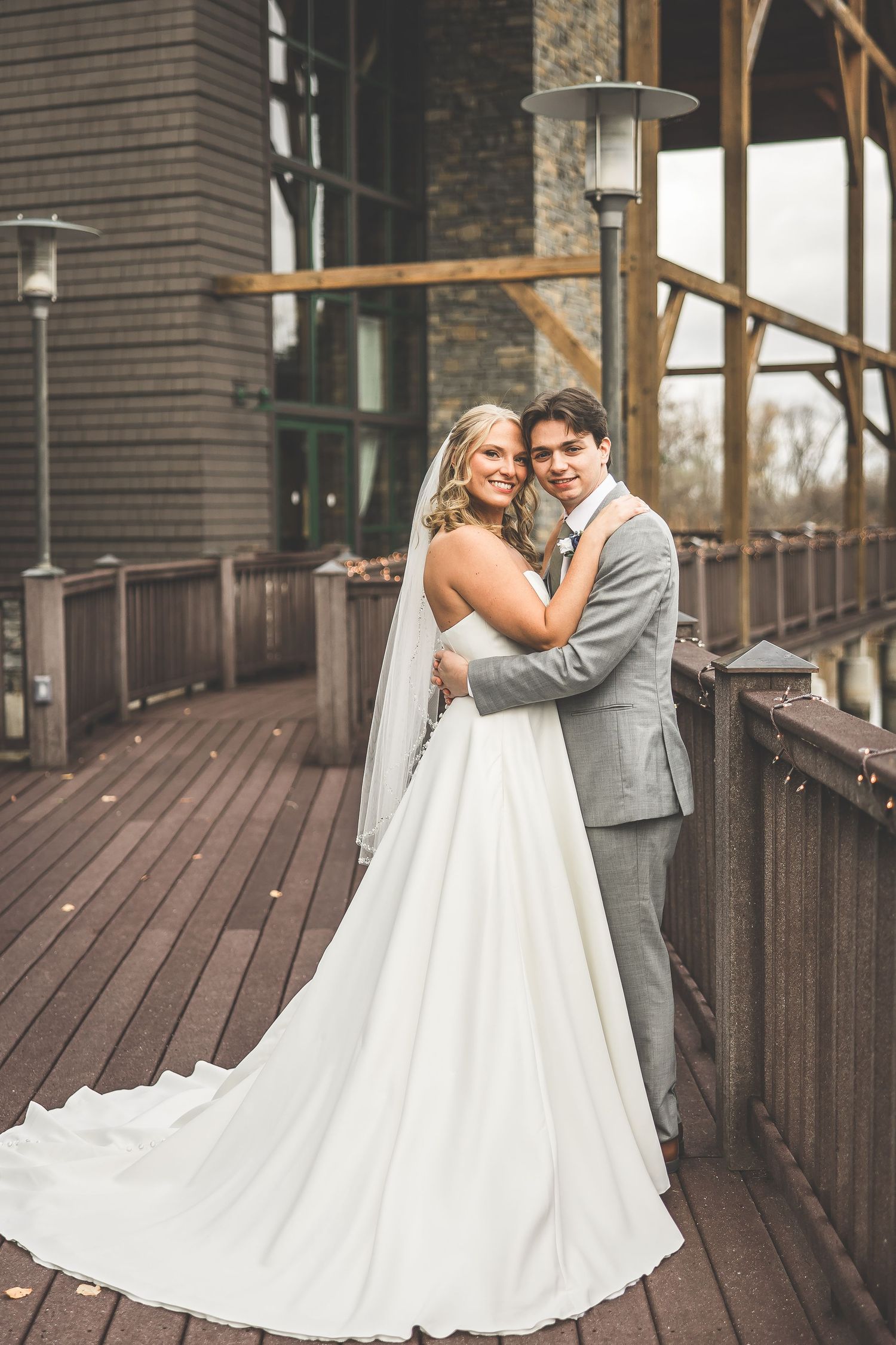 Wedding couple dances together on wooden deck of rustic lodge venue.