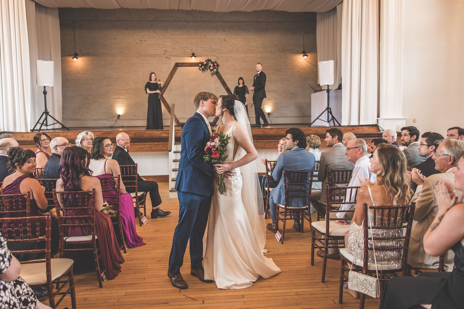Panoramic view of wedding ceremony with guests seated in elegant venue with wooden details.