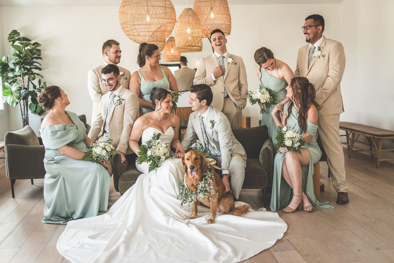 Casual wedding party photo with bridal party lounging in modern indoor setting.