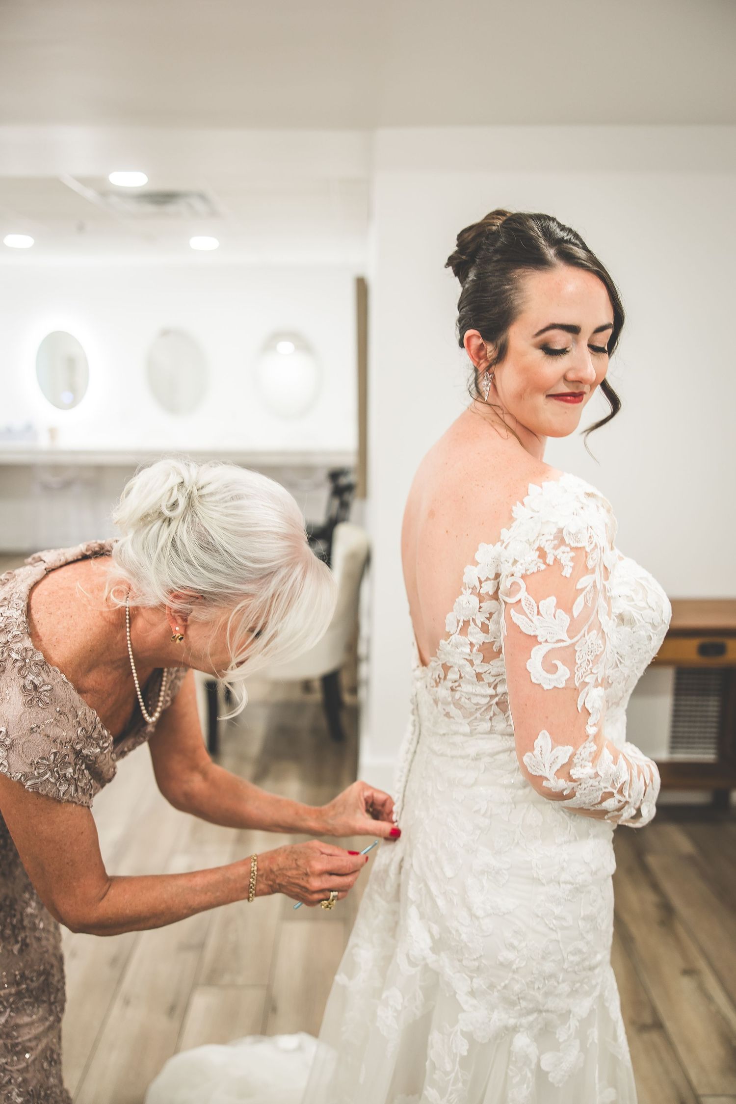 Close-up shots of a wedding dress being buttoned and adjusted, showing delicate lace patterns and details.